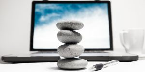 Rock balancing stone stack placed in front of a laptop