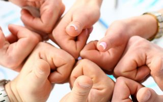 Group of people joining hands with thumbs up