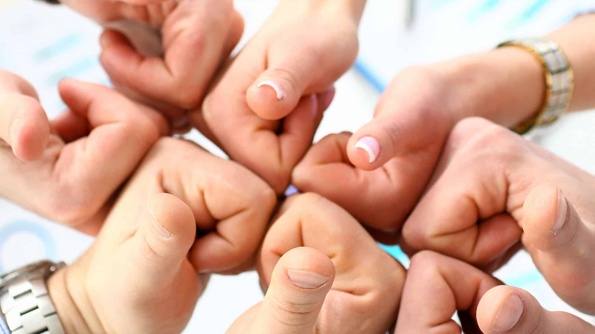 Group of people joining hands with thumbs up