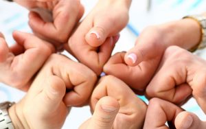 Group of people joining hands with thumbs up