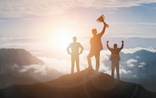 Victory Concept, Group of businesspeople on top of a mountain raising hands with a trophy